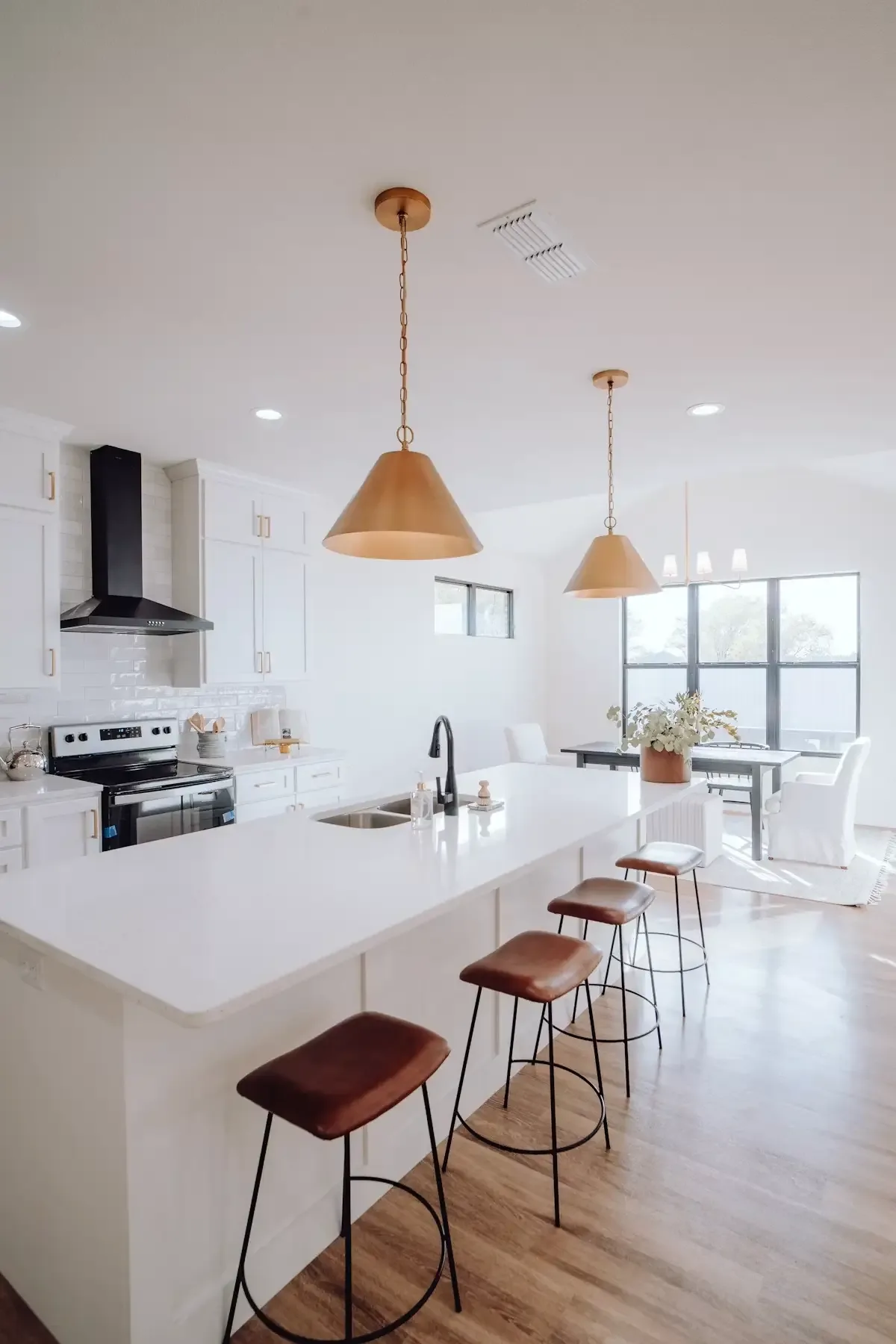 Bright open-concept kitchen with white cabinetry opening into a dining and living area