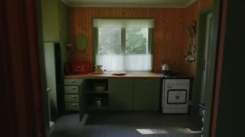 Dated green wood-paneled kitchen with vintage stove before renovation