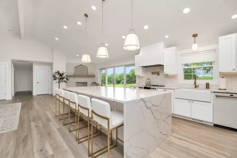 Renovated kitchen with white quartz waterfall island and brass accents