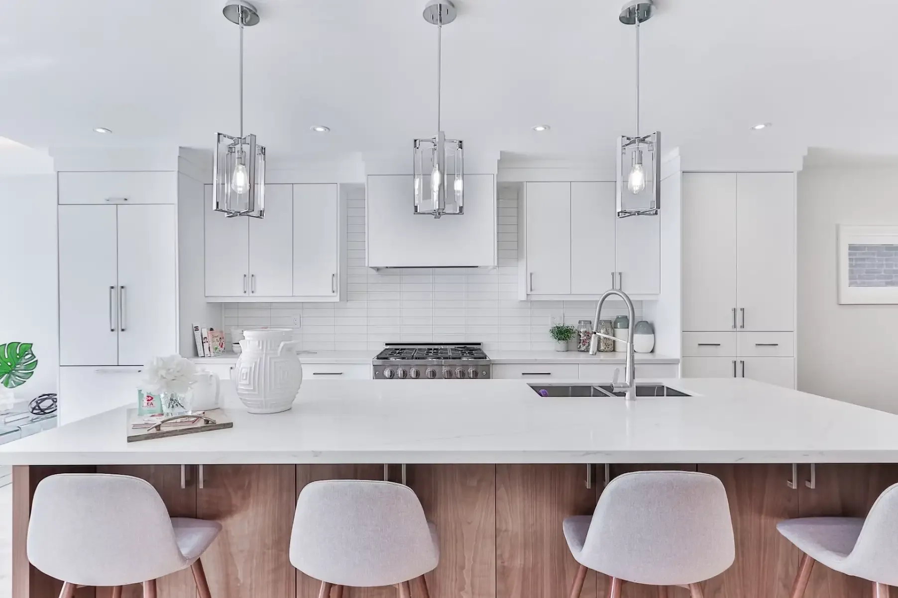 Modern white kitchen with walnut island base and glass pendant lighting