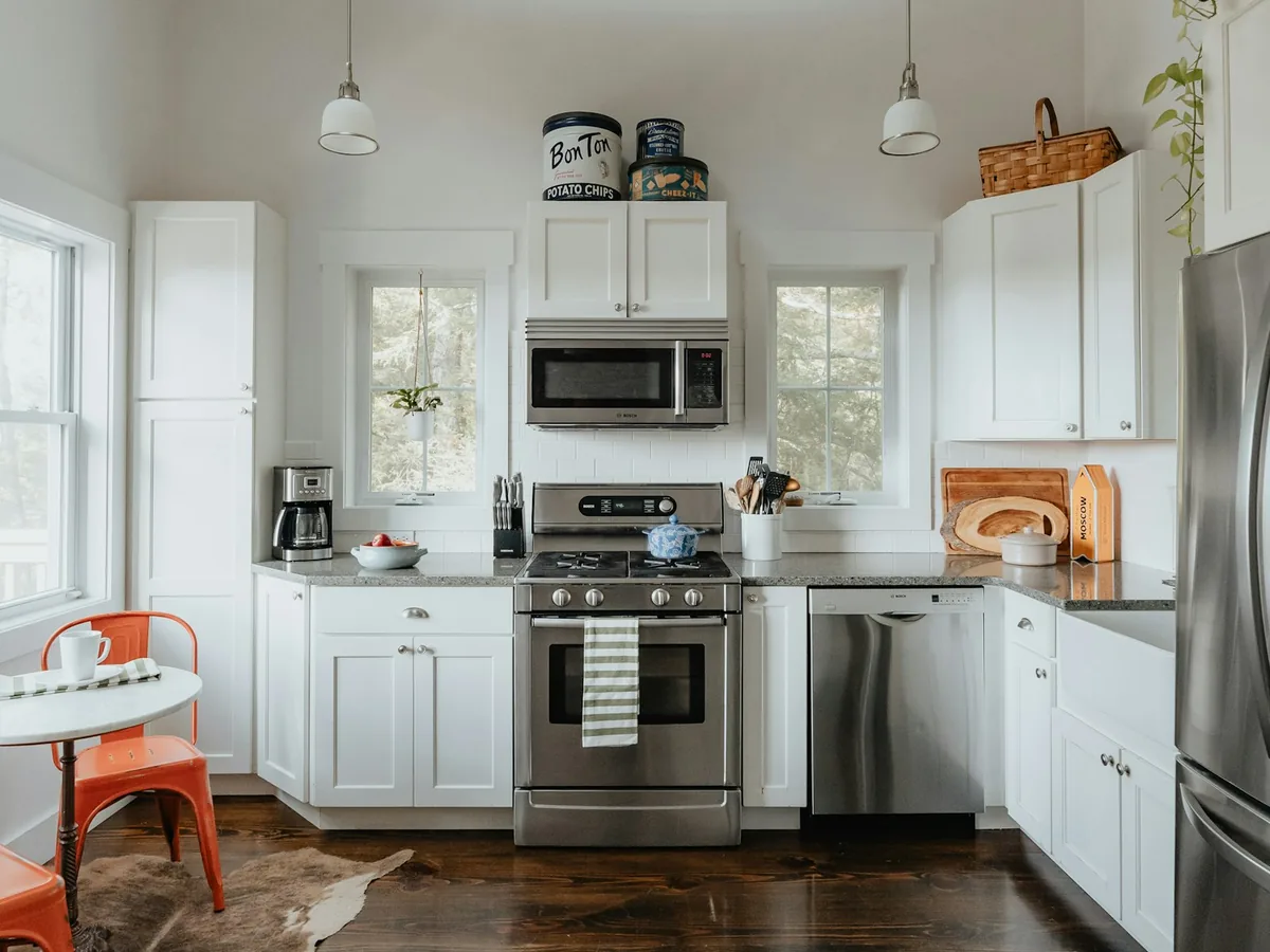 Traditional white kitchen with stainless steel appliances, granite counters, and dark hardwood flooring