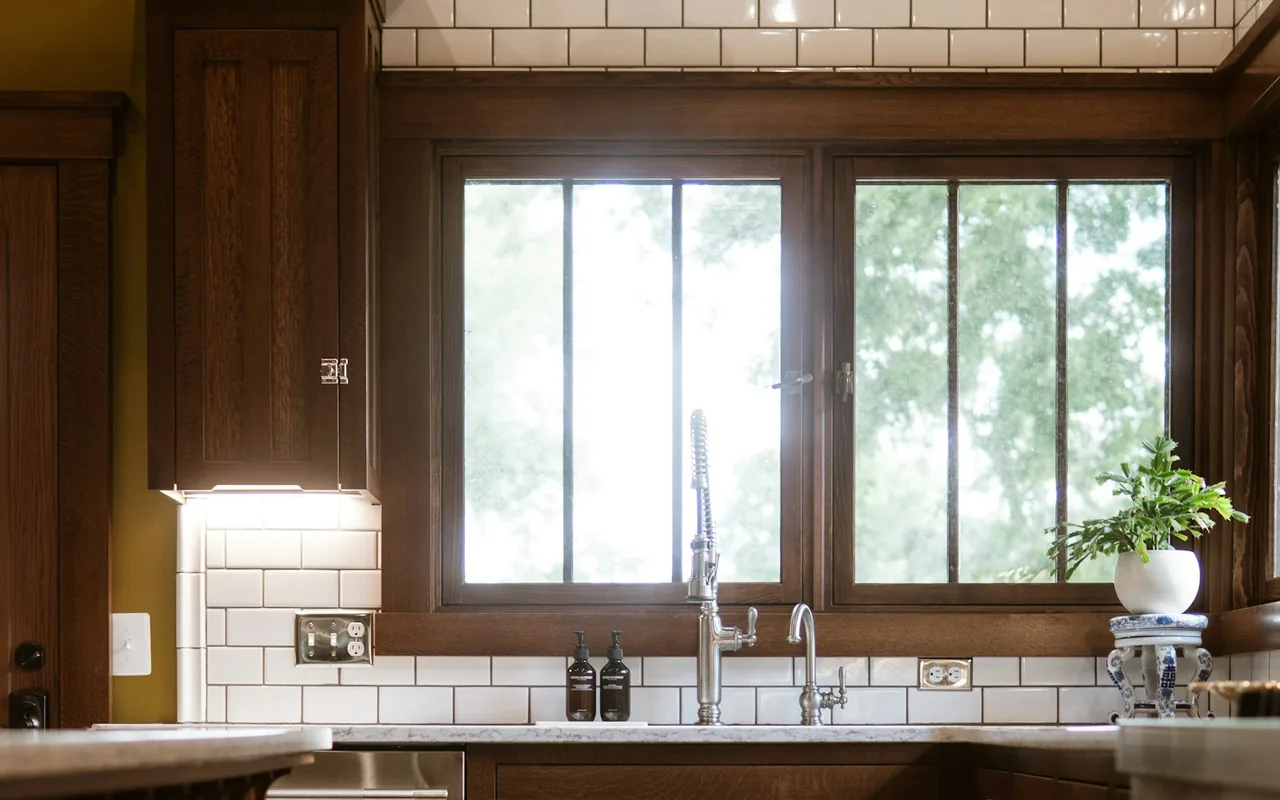 Craftsman-style kitchen with dark stained wood cabinetry, subway tile backsplash, and a wood-framed window